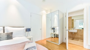 Un dormitorio moderno con cama, mesita de noche y un espejo grande.