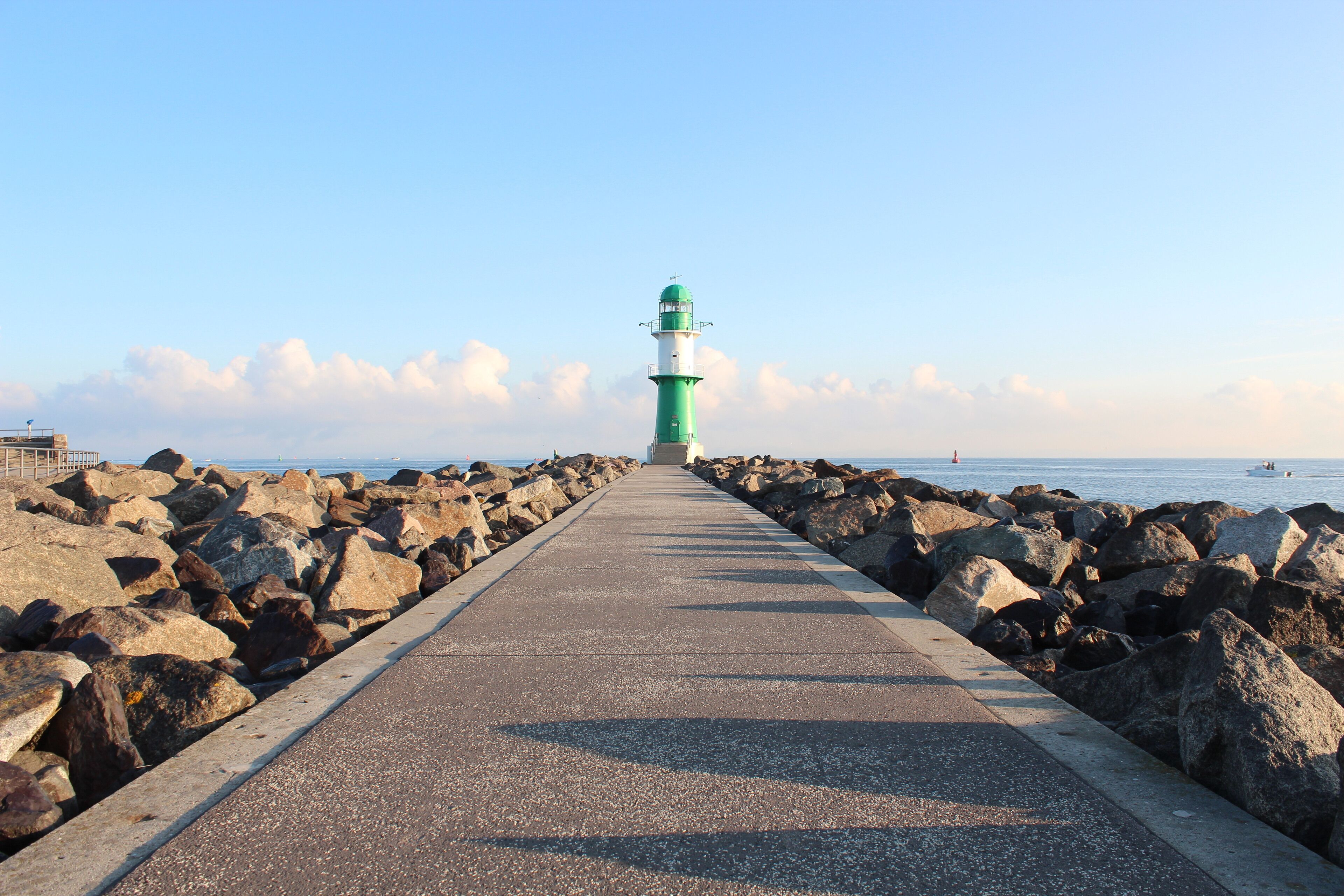 Un sentier menant à un phare, d’où l’on a une vue dégagée sur la mer et le ciel.