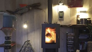 Huoneessa on puukamiina, metalliveistos ja kirjahylly täynnä kirjoja.