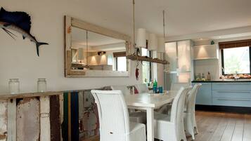 A dining area with a wooden table and chairs, a large mirror, and a decorative fish on the wall.