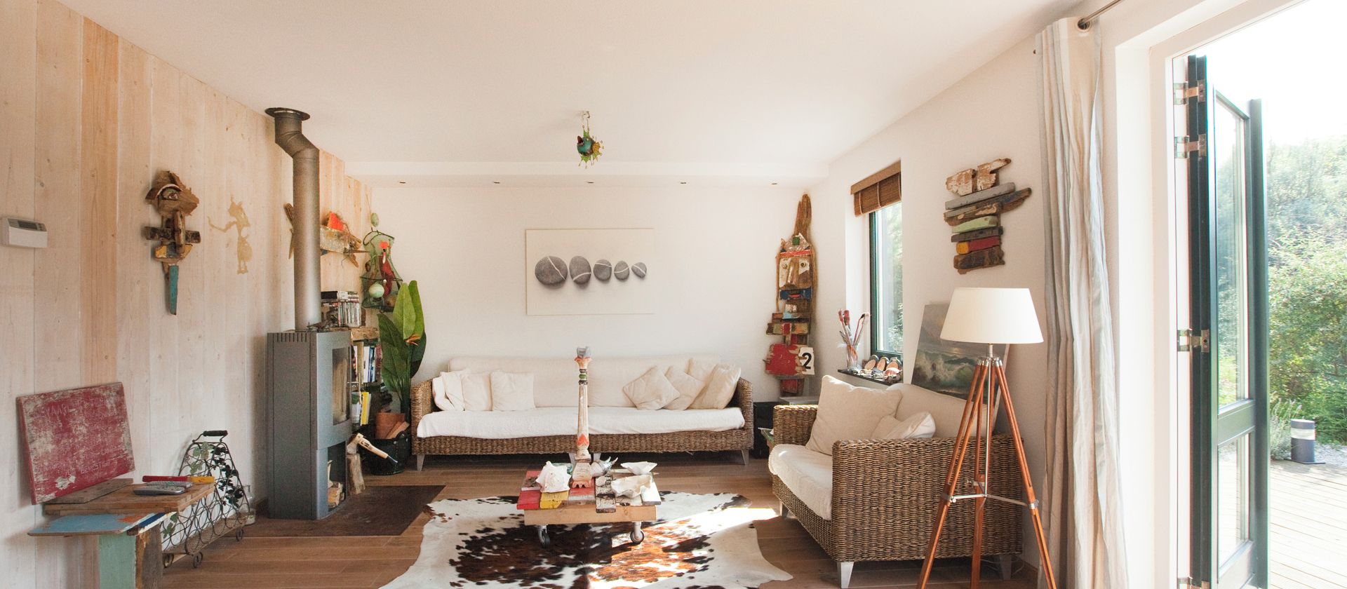 Uma sala de estar acolhedora com decoração rústica, apresentando um tapete de couro, móveis de vime e diversas obras de arte.