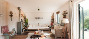 Uma sala de estar acolhedora com decoração rústica, apresentando um tapete de couro, móveis de vime e diversas obras de arte.