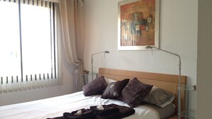 Uma cama bem arrumada com cabeceira de madeira, luminária de cabeceira e um quadro na parede.