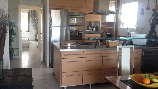 Uma cozinha moderna com eletrodomésticos de aço inoxidável, armários de madeira e uma ilha central.