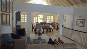 A spacious living area with a sofa, coffee table, and dining table. There are framed pictures on the walls and a ceiling fan. - The beautuful Butterfly Villa situated in the exclusive Silver Sands estate (Duncans)