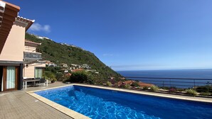 A swimming pool with a view of the ocean and hillside houses. -  Spacious villa,  180* ocean view, large heated pool, 5 min from Calheta beach (Calheta)