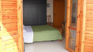 A bedroom with a bed, a chair, and a door.