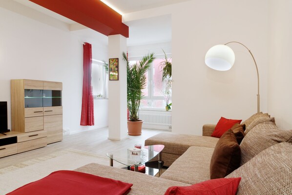 A modern living room with a sofa, a glass coffee table, a TV stand, and a floor lamp.