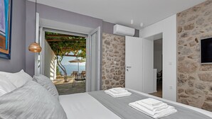 Ein Schlafzimmer mit einem Bett, Blick auf die Terrasse und einer Steinwand.