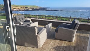 A deck with wicker furniture overlooking a coastal view. - A very special place (Co. Cork)