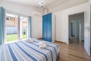 A bedroom with a bed, a blue door, and a view of a garden through a sliding door.