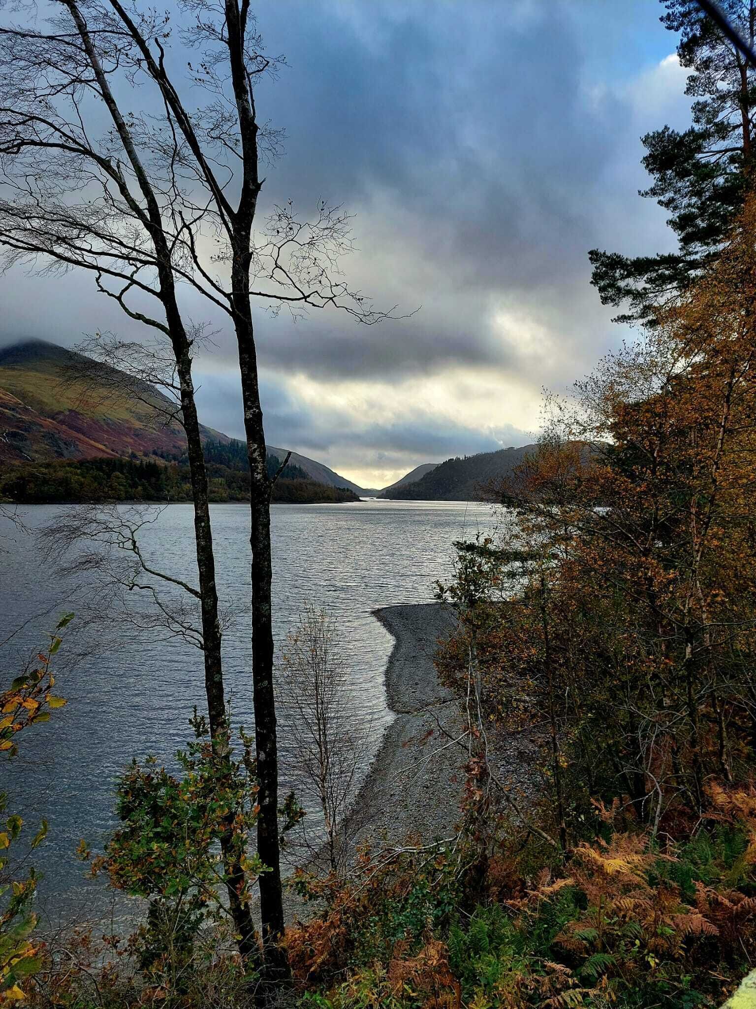 Un lac entouré de collines, avec des arbres au premier plan.