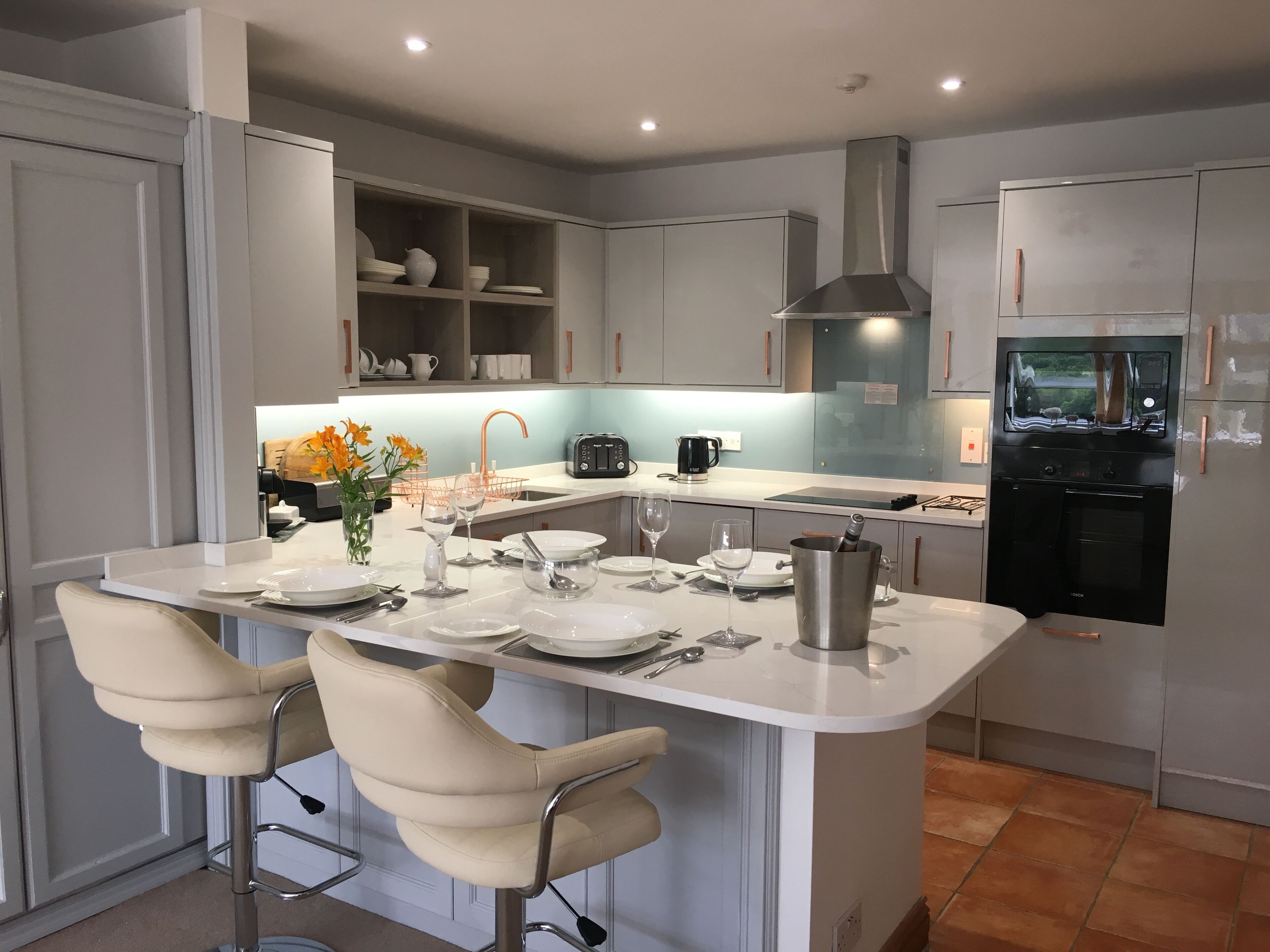 A modern kitchen with a central island, bar stools, a built-in oven, and a refrigerator.