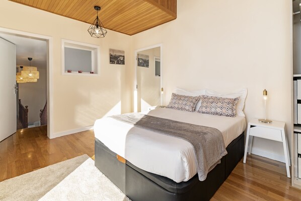 A bedroom with a large bed, a bedside table, a mirror, and a wooden ceiling. - Sky Villa, pool and view in a luxury urbanization. (Funchal)