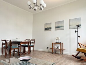 Ein Essbereich mit Holztisch und Stühlen, einem Glastisch und einer modernen Stehlampe.