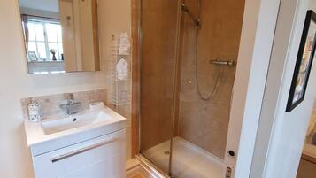 A bathroom with a white vanity, a glass shower enclosure, and a mirror.