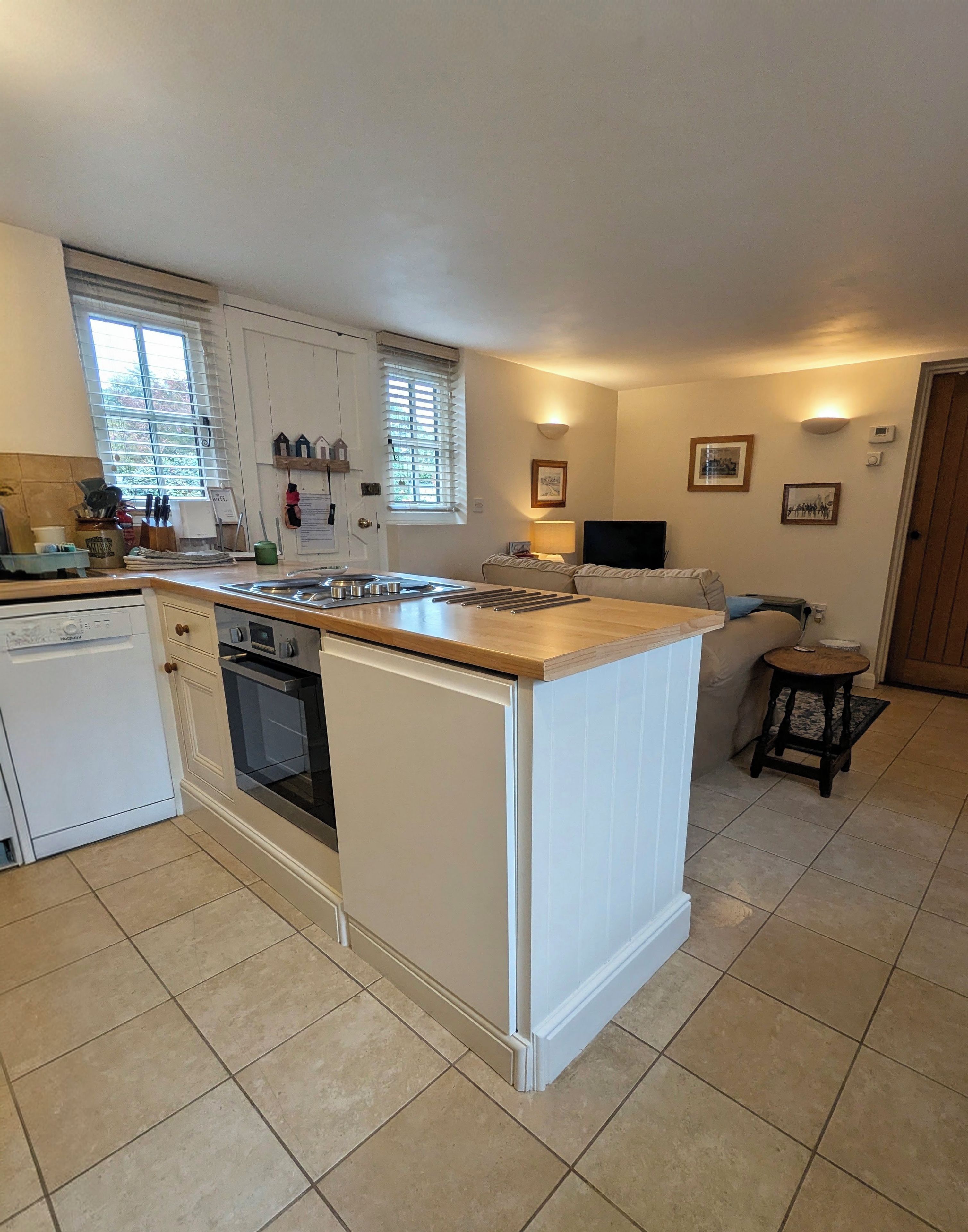 A kitchen with a central island, white cabinetry, a dishwasher, and a stove.