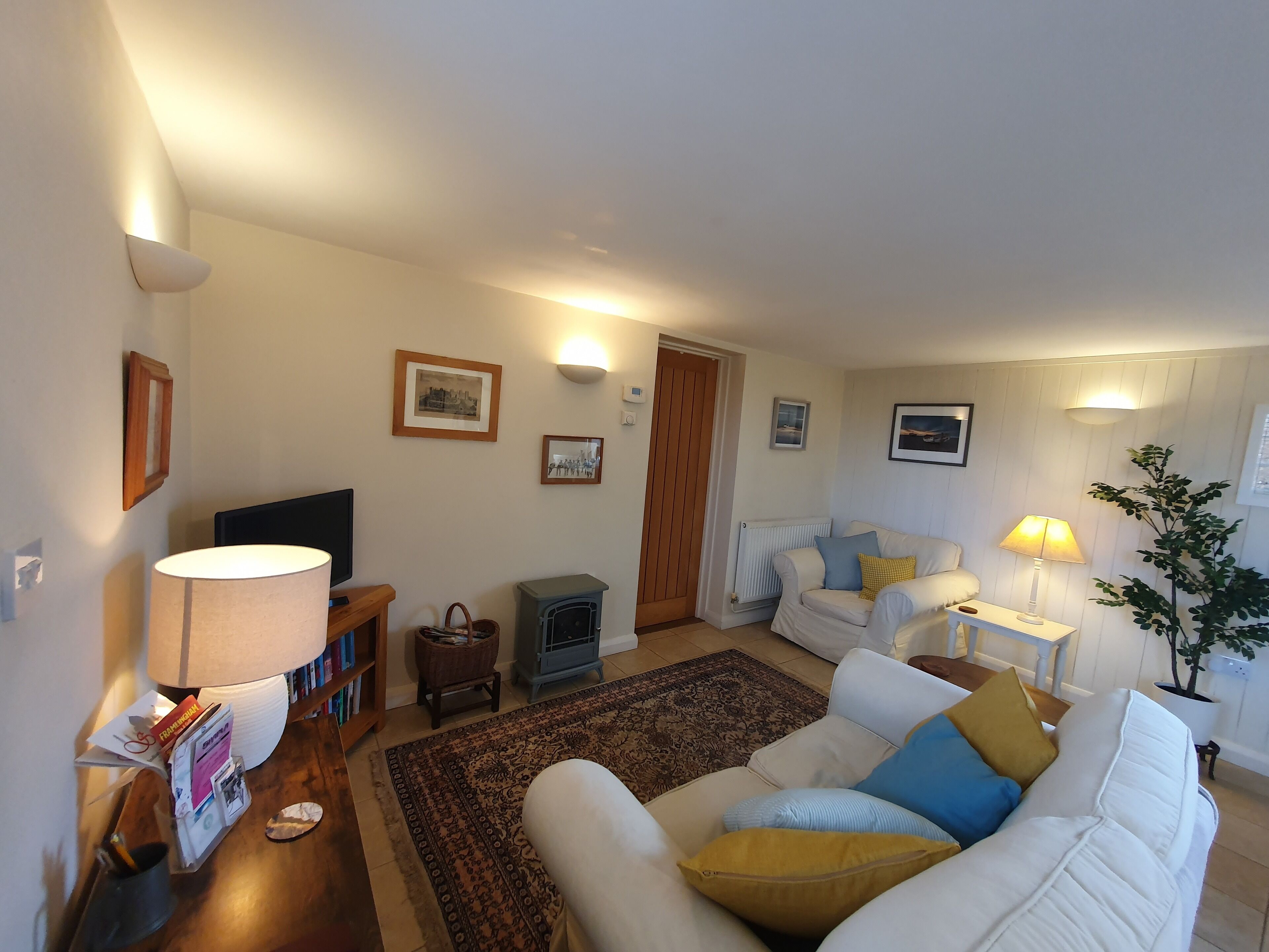 Una sala de estar con sofá, televisión, lámpara, chimenea y un cuadro en la pared.