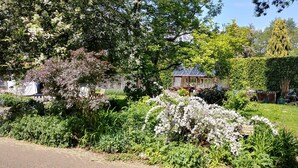 A garden with a gazebo, a pathway, and a variety of plants. - Country Cottage Set In pretty Suffolk village with 2 local pubs, dog friendly (Lower Ufford)