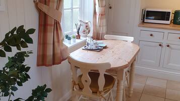 A cozy kitchen with a wooden table, a microwave, and a clock on the wall.
