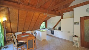 A spacious kitchen with wooden beams, a dining area with a table and chairs, and a small island with a sink. - Cozy, comfortably furnished apartment for up to 7 people with balcony (Immerath)
