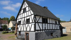 A traditional half-timbered house with a steeply pitched roof, a small front porch, and a cobblestone pathway leading to the entrance. - Cozy, comfortably furnished apartment for up to 7 people with balcony (Immerath)