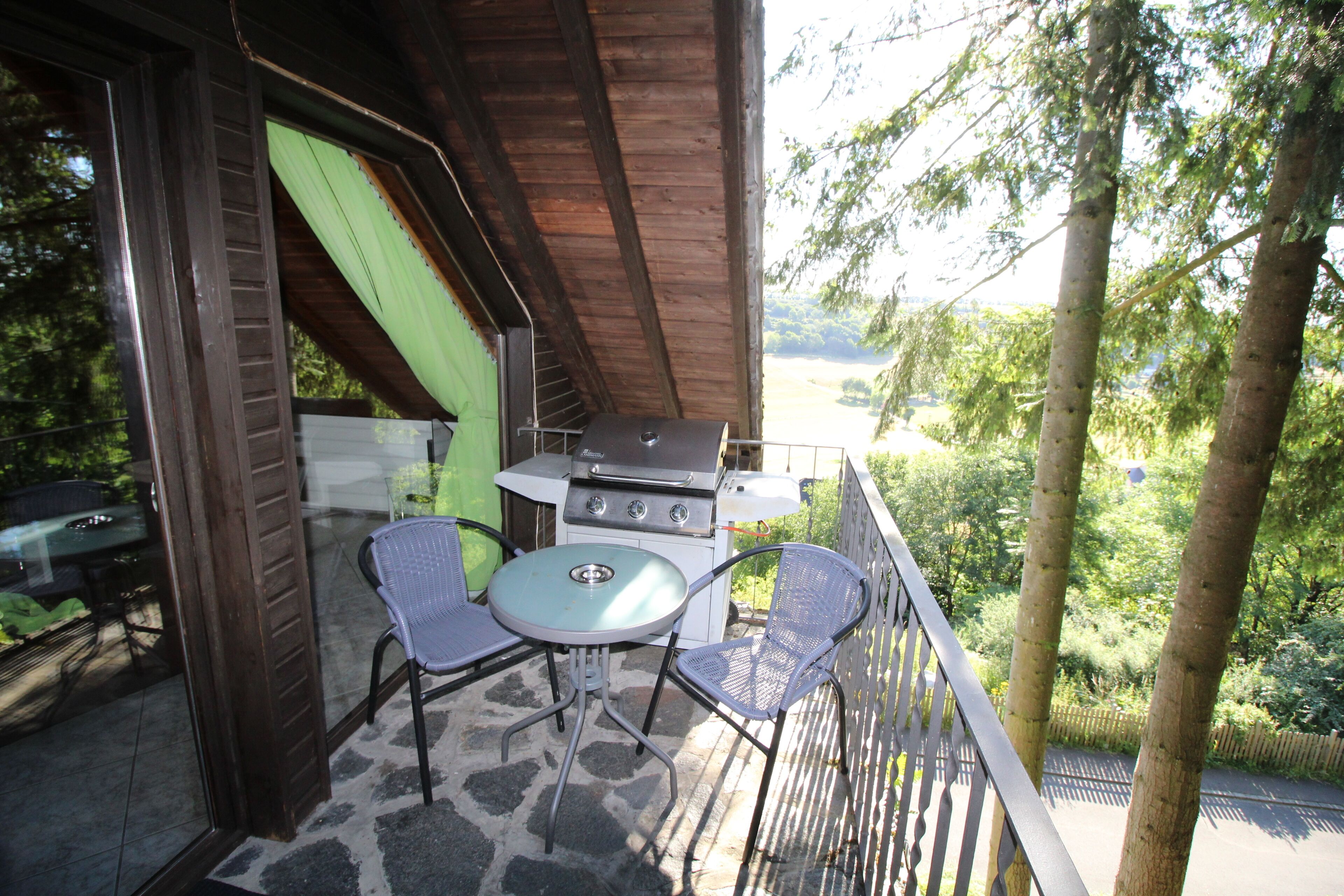 Une terrasse extérieure avec un barbecue, deux chaises et une table.