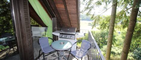 Une terrasse extérieure avec un barbecue, deux chaises et une table.