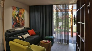 A modern living room with a black sofa, a yellow armchair, and a colorful abstract painting on the wall. - S. Torcato Valley Houses - House 1 (Guimarães)