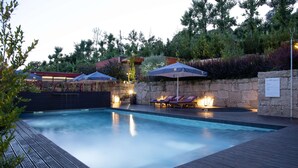 A swimming pool with lounge chairs and umbrellas, surrounded by stone walls and greenery. - S. Torcato Valley Houses - House 1 (Guimarães)
