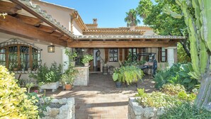 Ein Innenhof mit gefliestem Patio, Blumentöpfen und einem rustikalen Gebäude mit Ziegeldach.