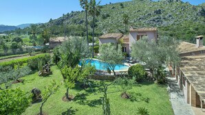 Eine Villa mit Swimmingpool, umgeben von üppiger Vegetation und einer gebirgigen Kulisse.