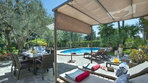 Eine Außenpatio mit Pool, Liegestühlen und einem Esstisch.
