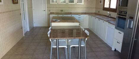 Una cocina con una isla central, armarios blancos y electrodomésticos de acero inoxidable.