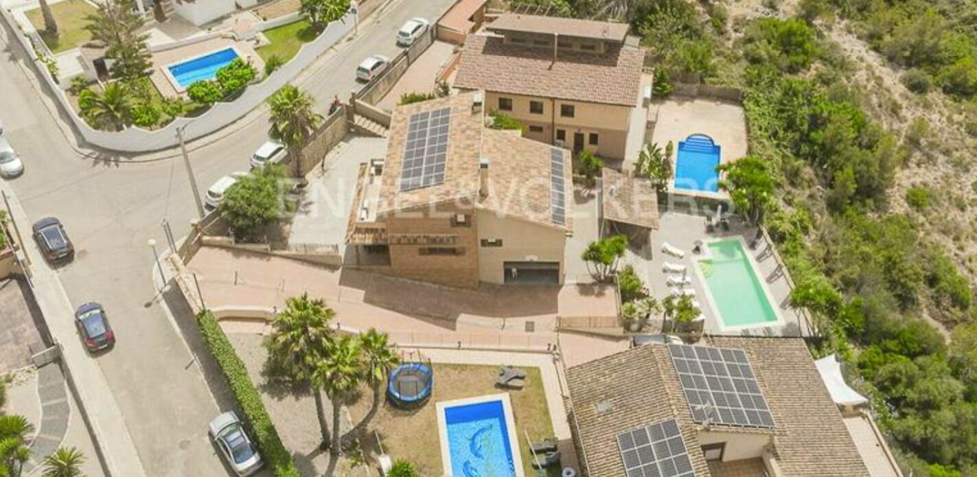 A residential property with a swimming pool, solar panels, and a road with cars.