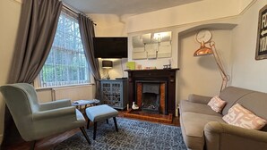 A living room with a fireplace, a sofa, a chair, a small table, and a patterned rug. - Spacious 3 bed holiday cottage in Hunstanton only 150 metres to the beach. (Hunstanton)