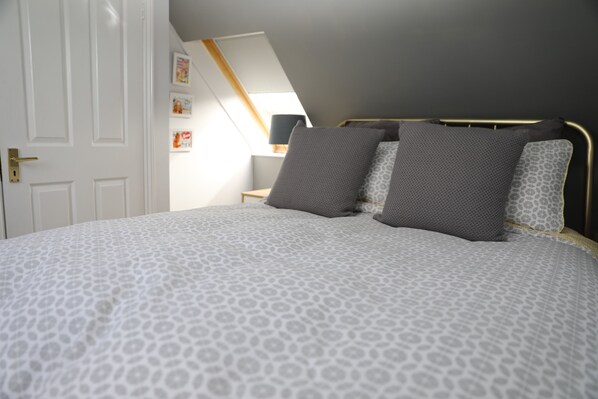 A bedroom with a bed, a nightstand, and a wall-mounted lamp.