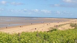 A wide beach with people walking and standing, and a clear sky. - Spacious 3 bed holiday cottage in Hunstanton only 150 metres to the beach. (Hunstanton)