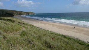 A coastal beach with a grassy foreground and a clear sky.