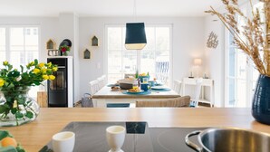 A modern kitchen with a wooden table, a black countertop, and a hanging light fixture.