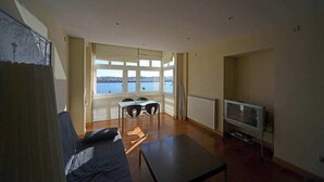 Una sala de estar con sofá, una mesa de centro, televisor y un comedor con sillas y una mesa.