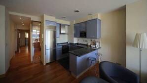 Una cocina moderna con electrodomésticos de acero inoxidable, una isla central y taburetes de bar.