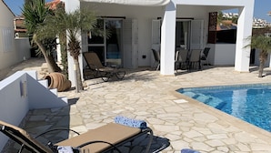 Una casa de dues plantes amb piscina, espai d'estar a l'exterior i jardí.