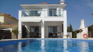 Un edifici blanc de dues plantes amb una piscina al davant.