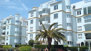 A multi-story hotel with balconies, a swimming pool, and palm trees. - SPECIAL FAMILIES, WI-FI, BEACH, POOL, SPORTS TRACKS (Málaga, Benalmádena)