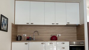 A modern kitchen with white cabinets, a stainless steel sink, a kettle, and a built-in oven. - Immaculate Apartment,  Uninterrupted Stunning Bay Views , Private parking (Kotor)