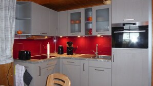 A compact kitchen with grey cabinets, a red backsplash, a black coffee maker, and a stainless steel oven. - The house is located right on the edge of the Müritz National Park (Userin)