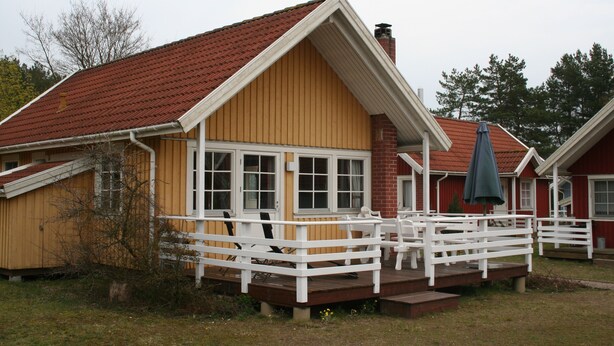 A two-story house with a red roof, white trim, and a wooden deck with white railings. - The house is located right on the edge of the Müritz National Park (Userin)