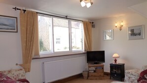 Ein Wohnzimmer mit Fernseher, Lampe und Möbeln mit Blumenmuster.