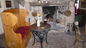 Ein traditionelles Pub-Interieur mit einer hölzernen Bank, einem Tisch mit Kerze und einem Kamin aus Ziegelsteinen.